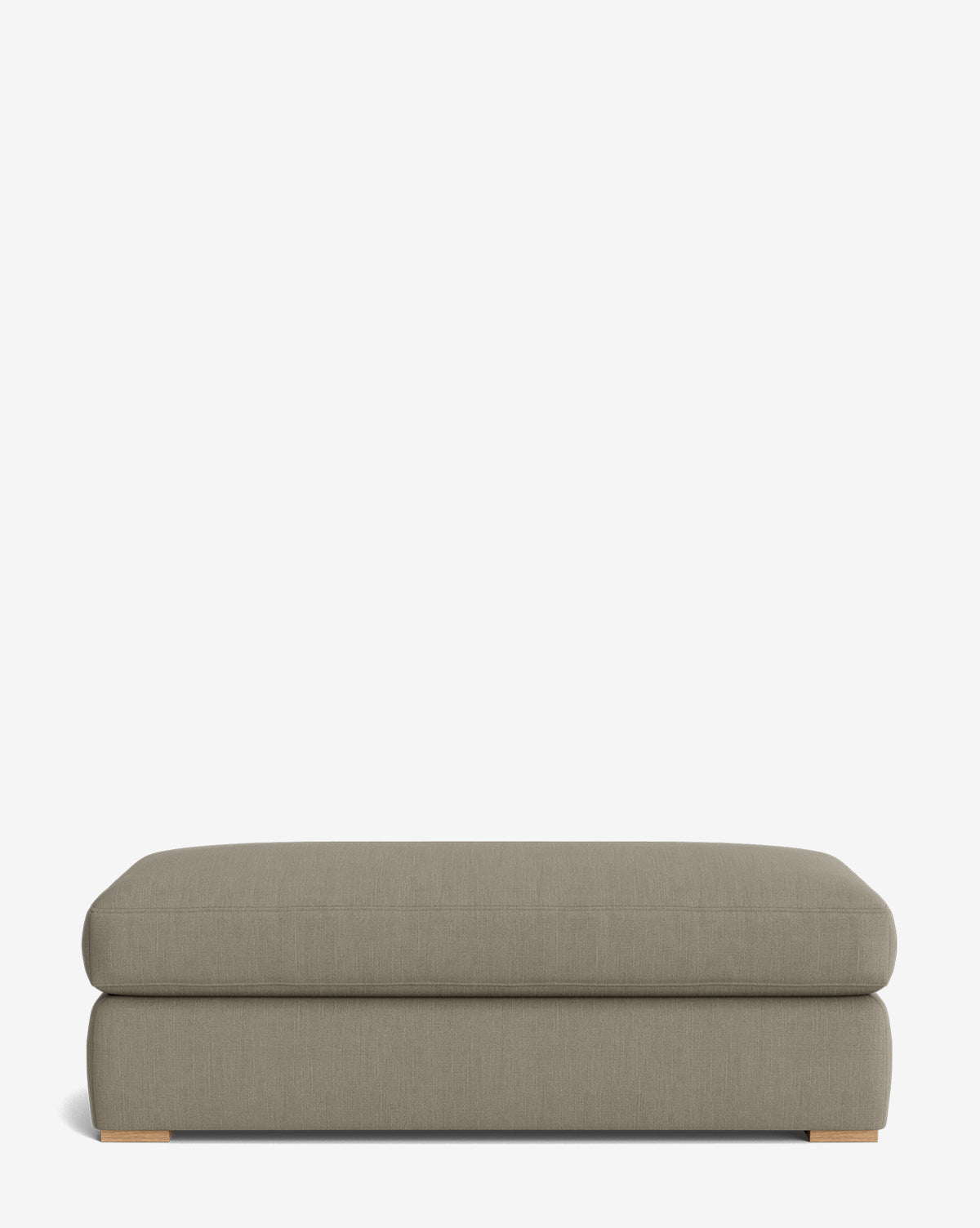 The Macy Upholstered Ottoman is a large, rectangular taupe piece with a smooth fabric surface and low wooden feet, perfect for versatile living room use, shown against a plain white background, by McGee & Co.
