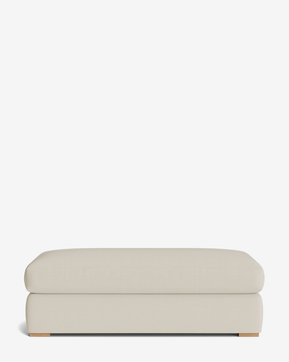 The Macy Upholstered Ottoman is a large, rectangular ottoman with rounded edges and low wooden feet, ideal as versatile living room furniture, shown against a plain white background, by McGee & Co.