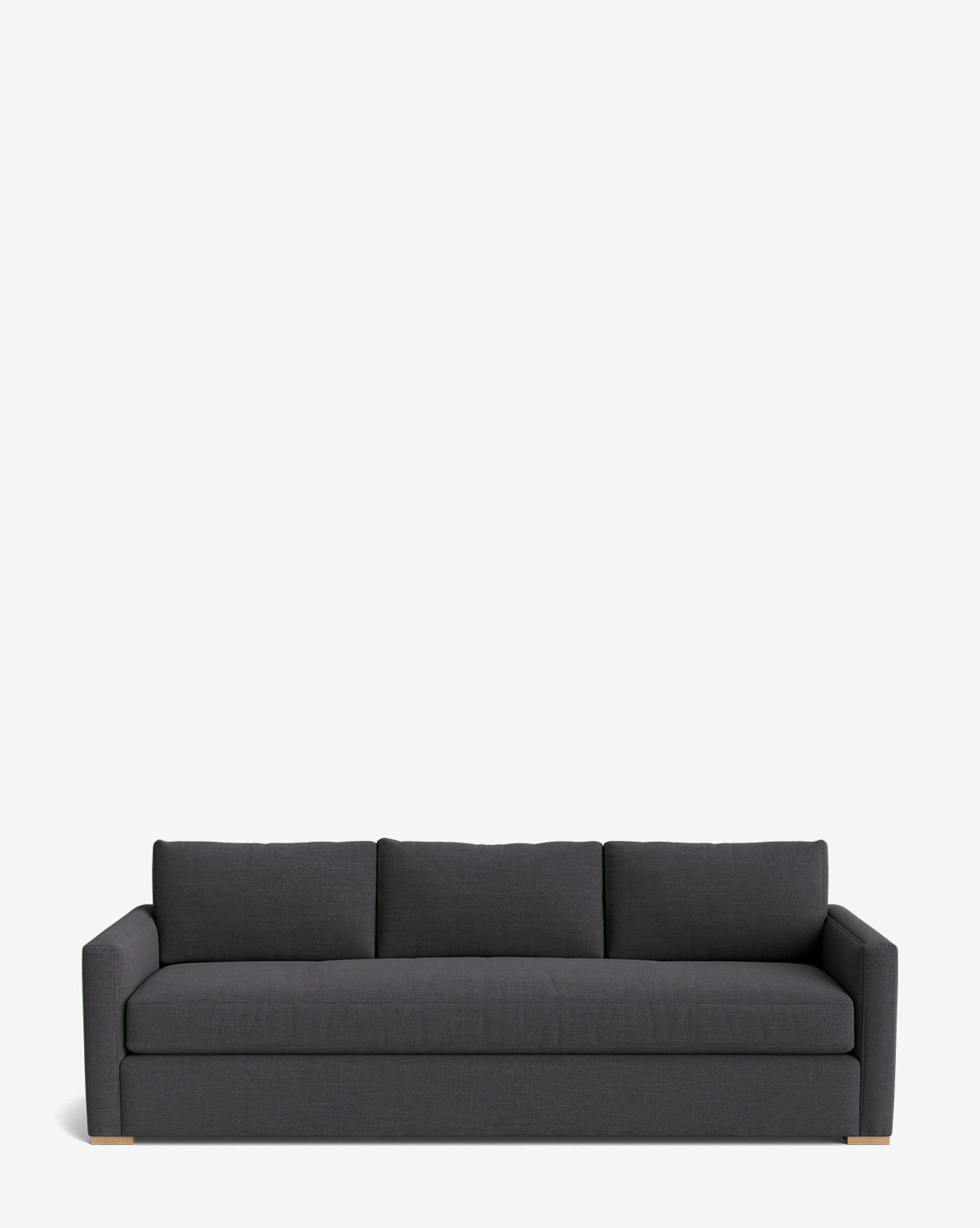 The Macy Upholstered Sofa (84-96) features dark gray upholstery, three seat and back cushions, low square arms, and wooden feet—an ideal modern touch for your living room—shown against a plain white background by McGee & Co.