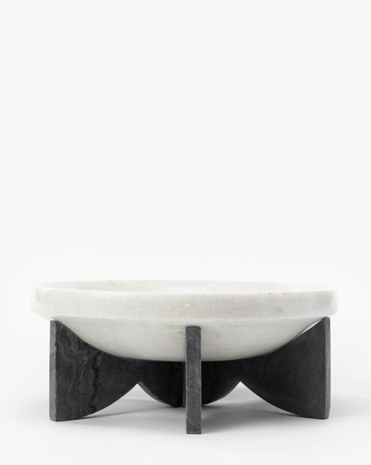 The Mahoney Bowl, crafted from white marble with a sculptural silhouette, sits atop a geometric black marble base featuring four intersecting supports, displayed against a plain white background by McGee & Co.