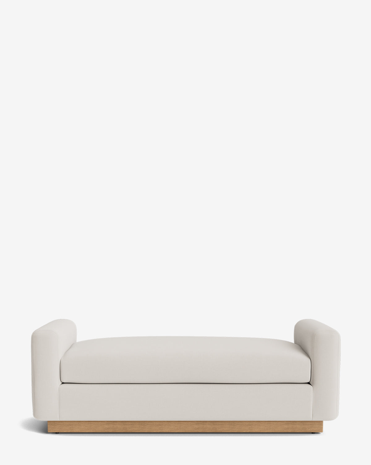 The Mansfield Bench is a modern, minimalist piece with light beige upholstery, low rounded armrests, and a wooden base, presented against a plain white background by McGee & Co.