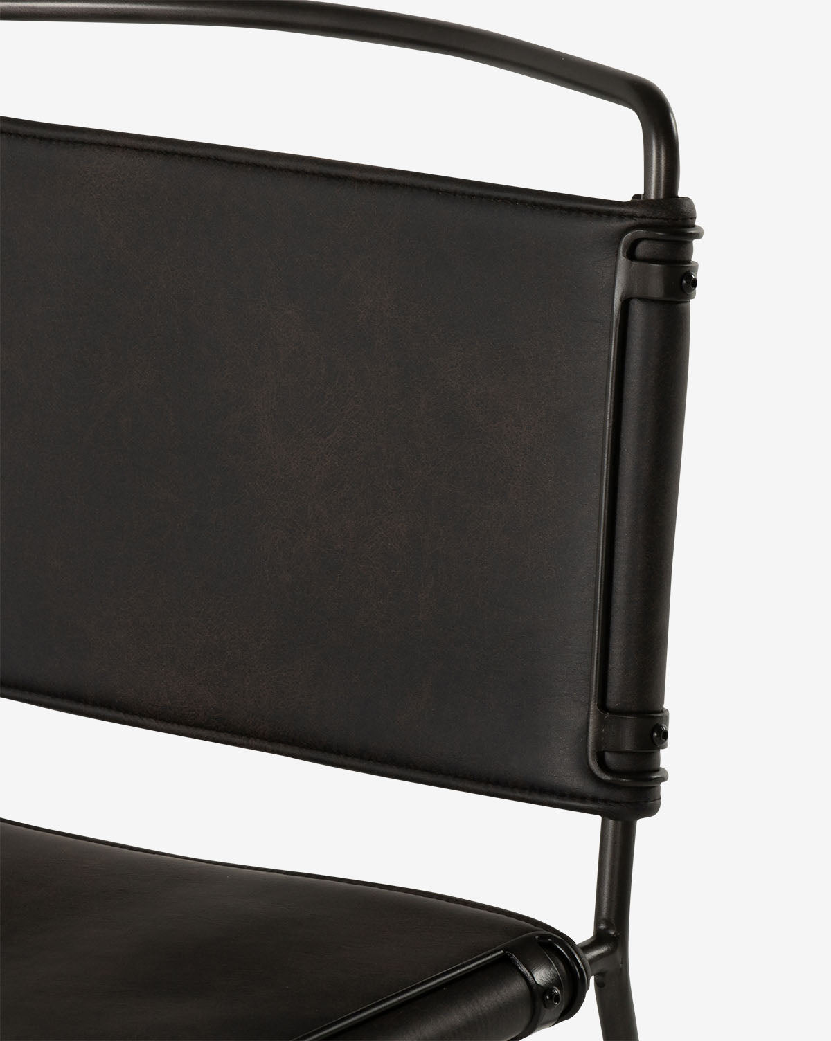 Close-up of the Moore Dining Chair, featuring a dark brown leather or faux leather backrest and seat, black metal frame, contoured canvas seating, and visible bolts for an industrial look by McGee & Co.