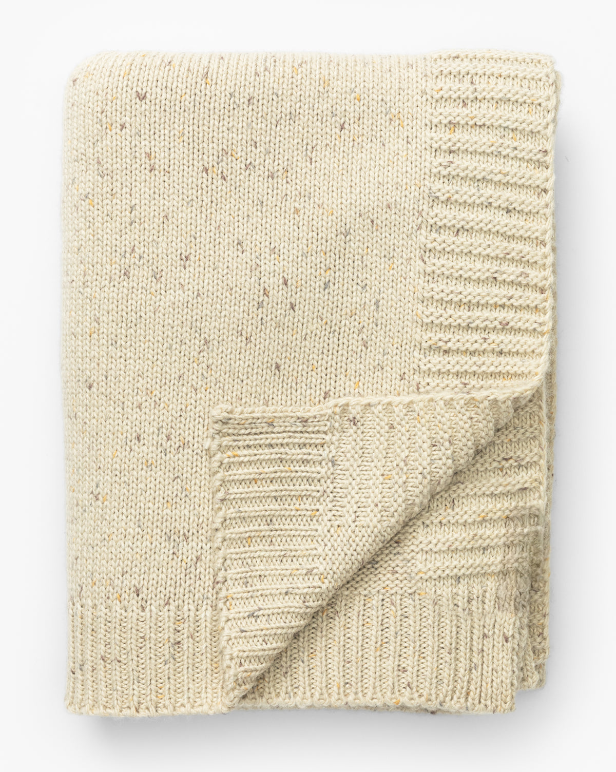The Otis Knit Throw by Makerspalm is a cozy wool-blend beige throw with grey-speckled fibers and ribbed edges, shown folded on a white background, McGee & Co.