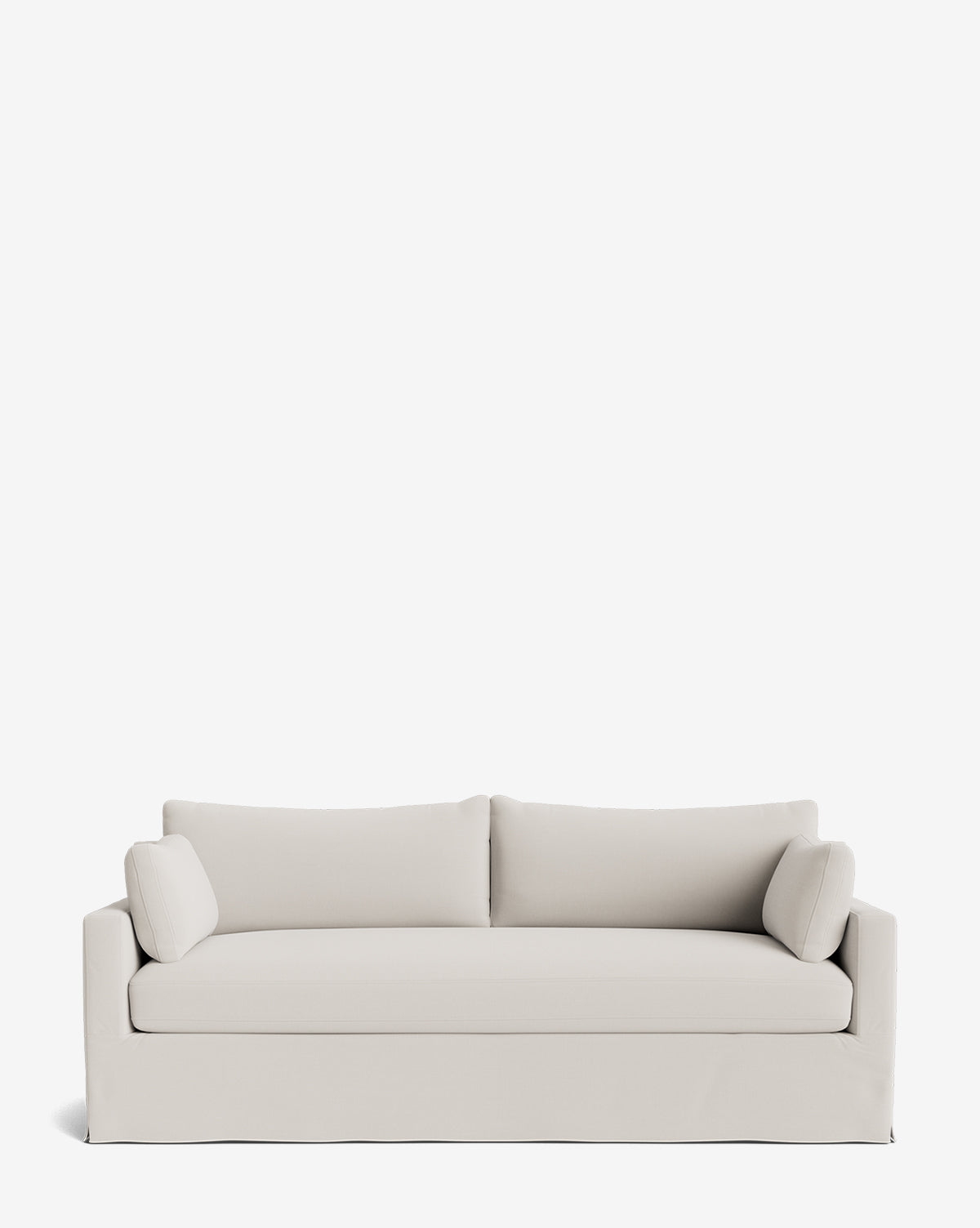 A modern light beige Peterson Classic Slipcover Sofa (75-100) with clean lines, feather blend cushions, and two cylindrical side pillows, set against a plain white background by McGee & Co.