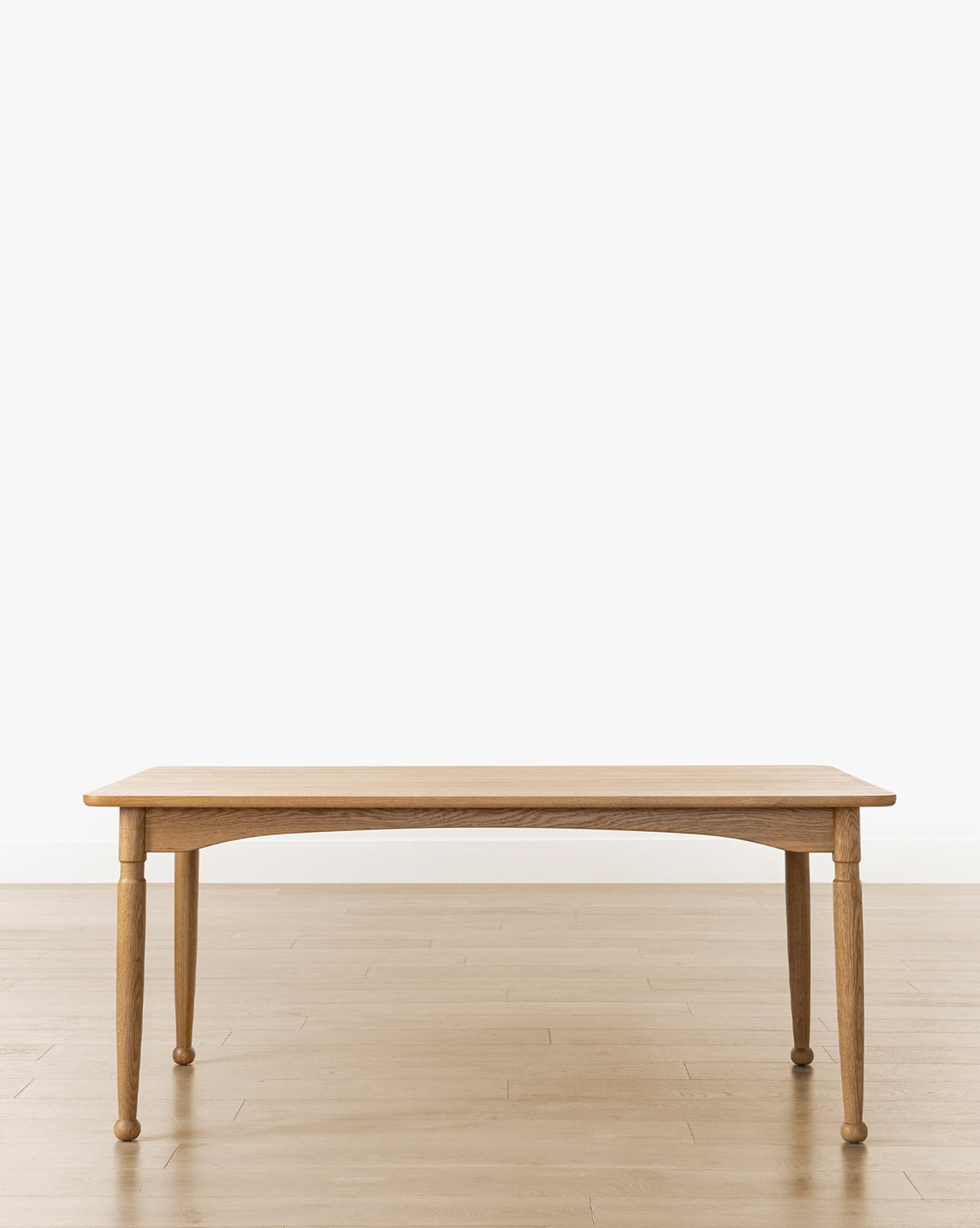 The Phipps Dining Table, featuring four legs, stands on a light wood floor against a plain white background, seamlessly blending timeless simplicity with modern traditional design, by McGee & Co.