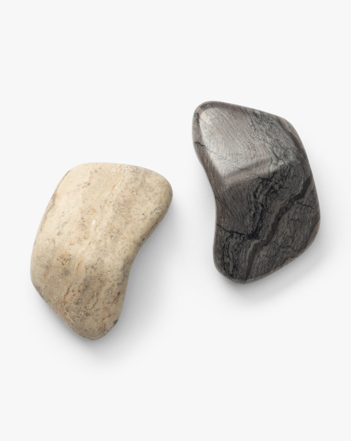The Piedra Objects (Set of 2) feature two smooth, irregularly shaped stones—one light beige like silver travertine marble and one dark gray with wavy streaks—on a white background, perfect for coffee table styling, by McGee & Co.