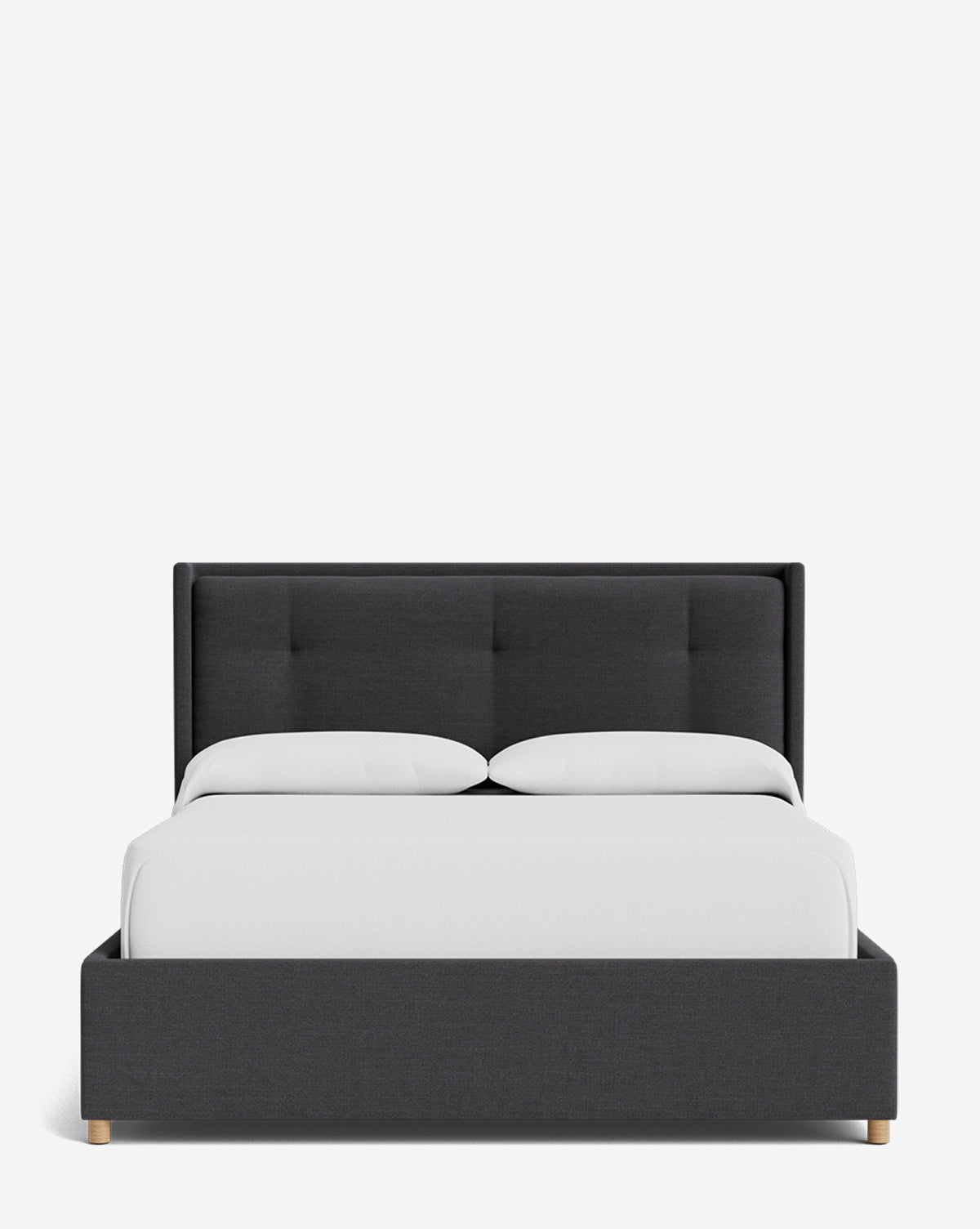 The Ria Bed Low Headboard is a modern, dark gray upholstered frame with a tufted headboard, styled with crisp white bedding and two pillows, displayed against a plain white background by McGee & Co.