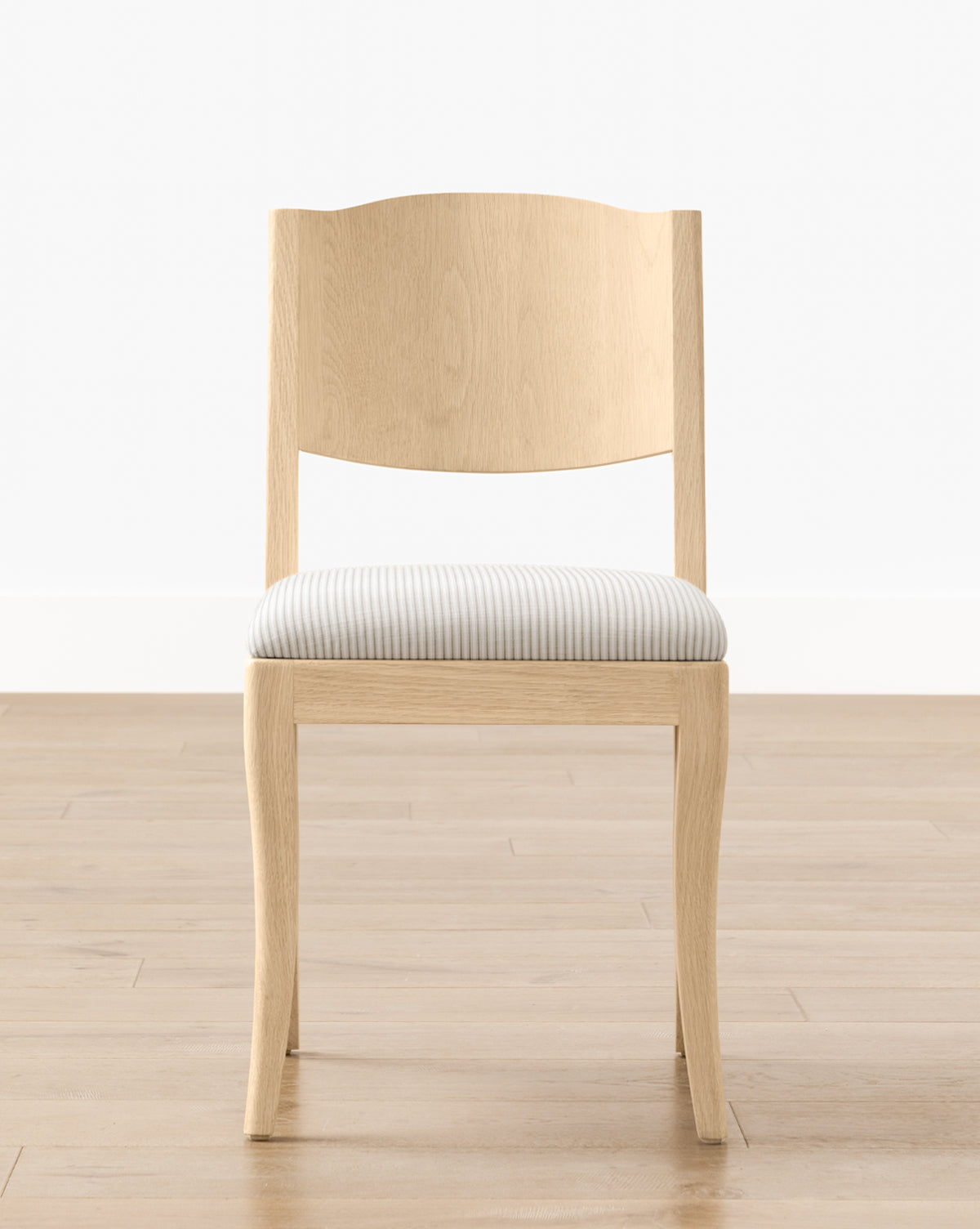The Shepherd Dining Chair has a light wood, white oak frame with a curved backrest and an upholstered seat in light gray and white stripes, shown on a wooden floor with a white wall by McGee & Co.