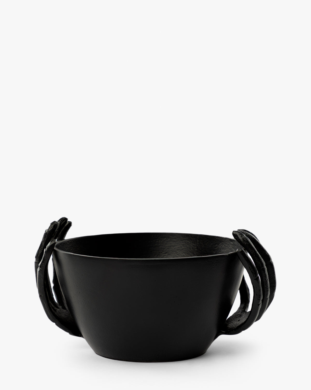 The Skeleton Hands Treat Bowl features two matte black sculpted hands on either side, creating a sleek, artistic look perfect for serving Halloween candy. Seen against a plain white background, it’s an eye-catching party centerpiece by McGee & Co.