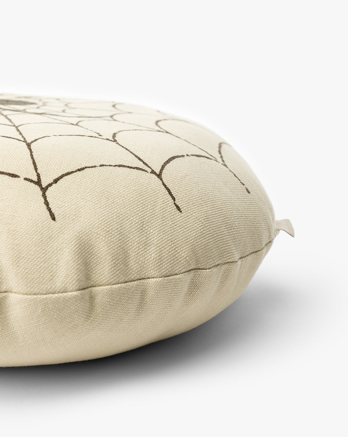 The Spider Pillow is a round, beige cushion with a simple black geometric line design—ideal as a subtle Halloween accent, by McGee & Co.