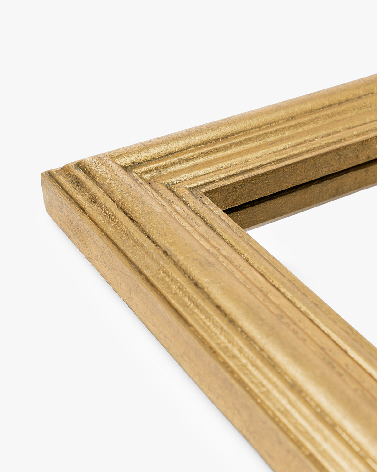 Close-up of the corner of the gold-colored Suzanne Wall Mirror frame, featuring a rectangular shape and textured ridged surface, photographed against a white background by McGee & Co.