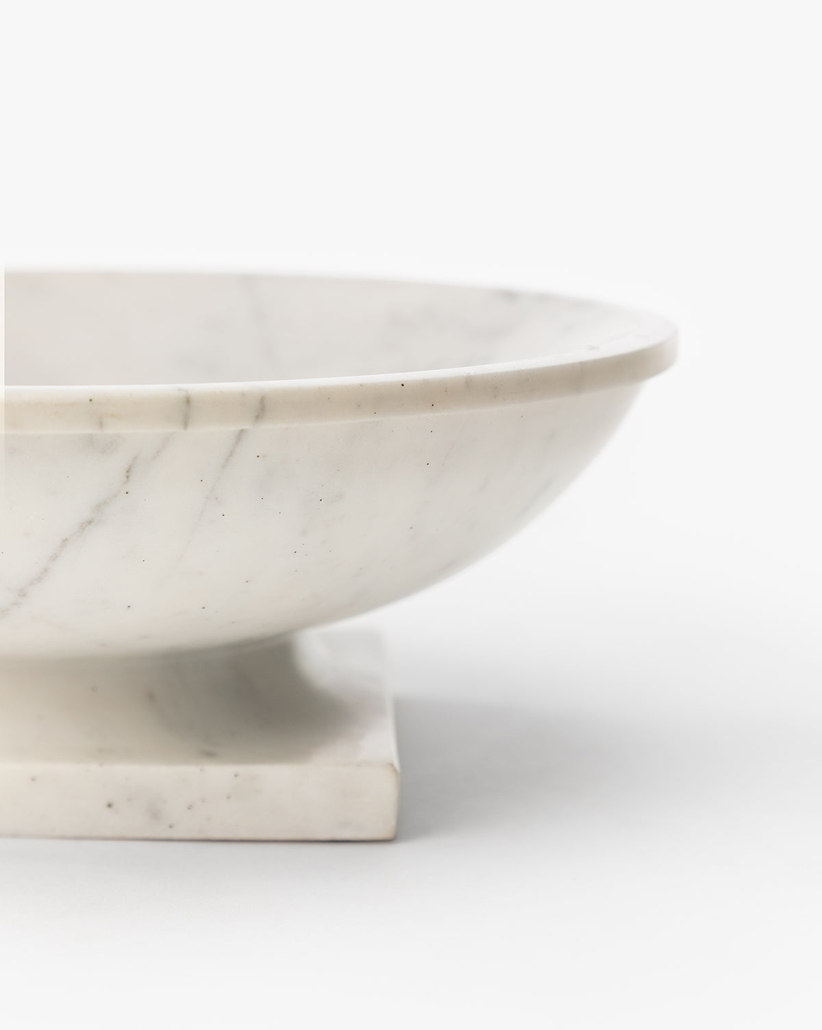 The Tayva Bowl, a sculptural white marble piece with subtle gray veining, is shown in close-up on a square base against a plain white background by McGee & Co.