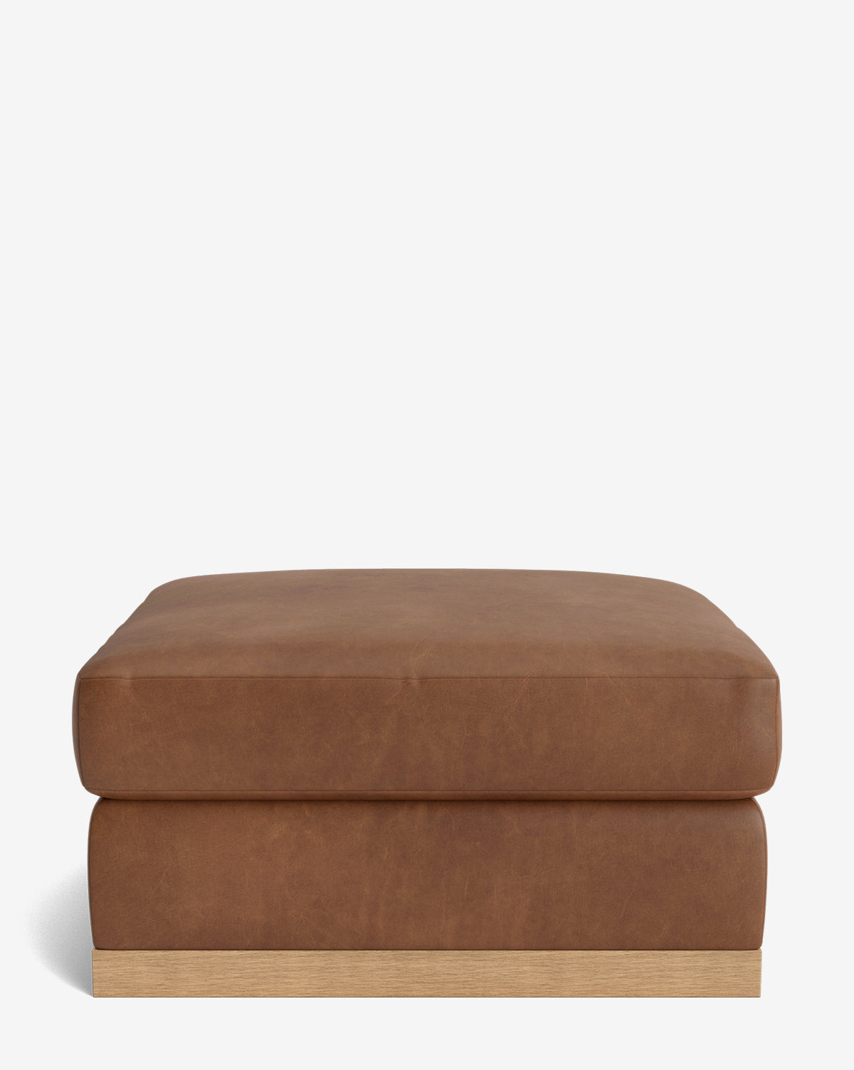 The Vernon Modular Ottoman, a large square piece with brown leather upholstery and a low wooden base, is displayed against a plain white background by McGee & Co.
