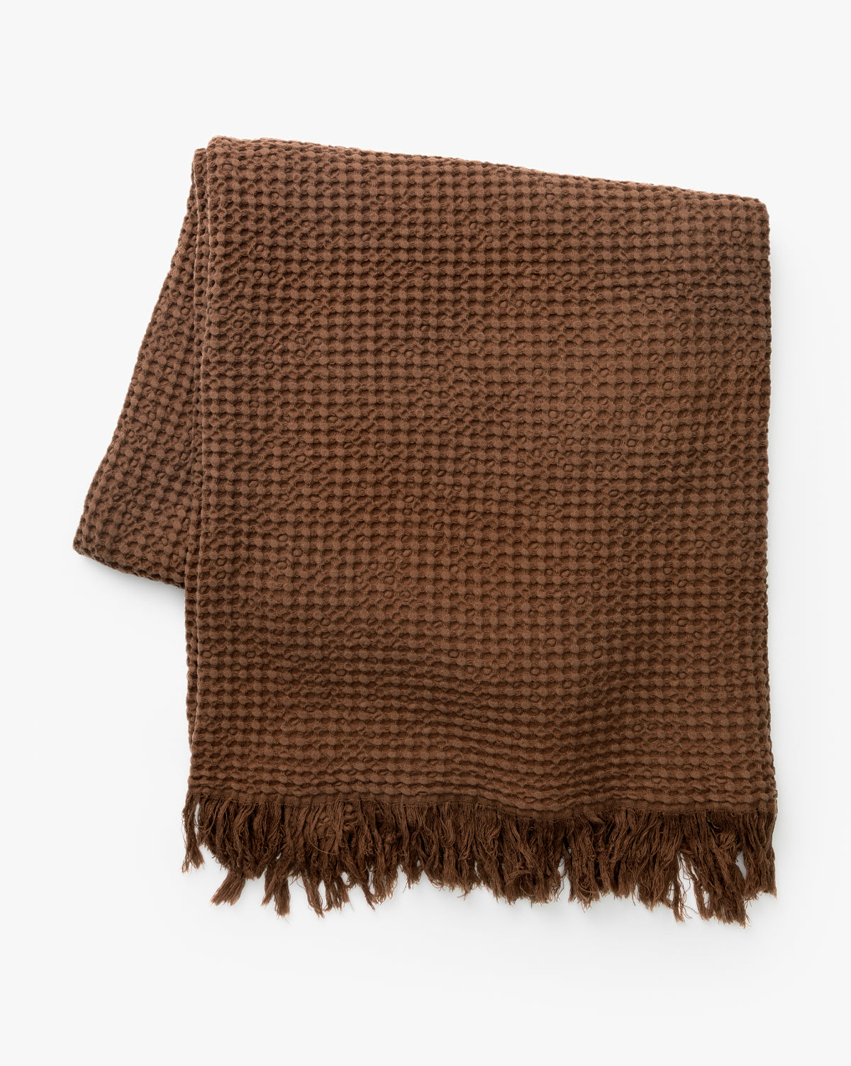 A folded Viola Throw artisanal blanket in brown, featuring a textured weave and fringed edges, is displayed on a white background, by McGee & Co.