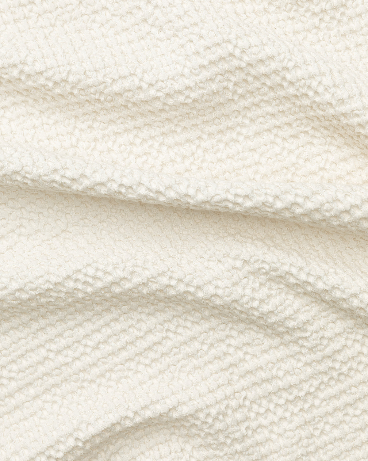Close-up of the Viola Throw’s off-white, textured bouclé fabric with a soft, looped surface and gentle folds, highlighting its unique artisanal weave, by McGee & Co.