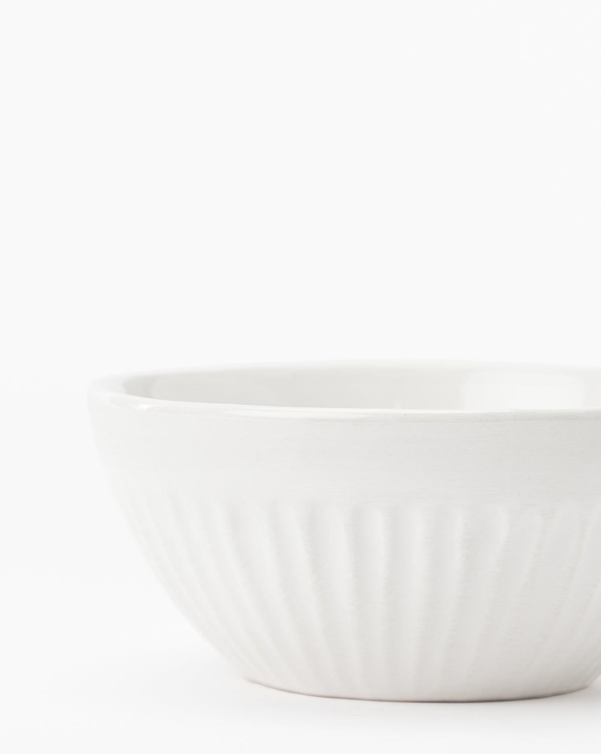 The Adele Bowl, featuring fluted detailing and a timeless white ceramic design, sits on a white surface against a plain white background by McGee & Co.