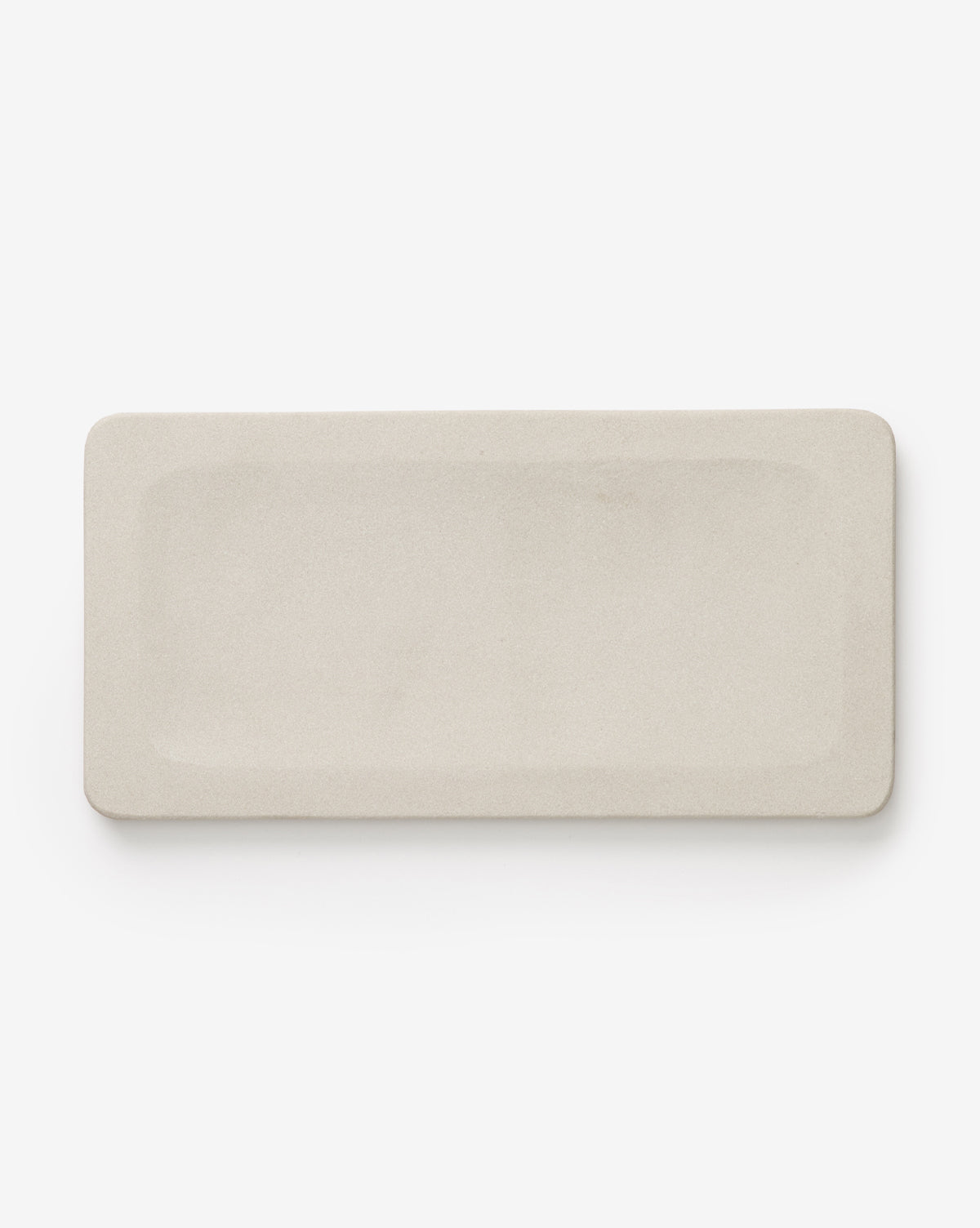 The Amada Sandstone Bath Collection features a rectangular, light beige ceramic plate with rounded corners and a smooth, minimalist design—perfect for adding an organic touch to your bathroom decor.