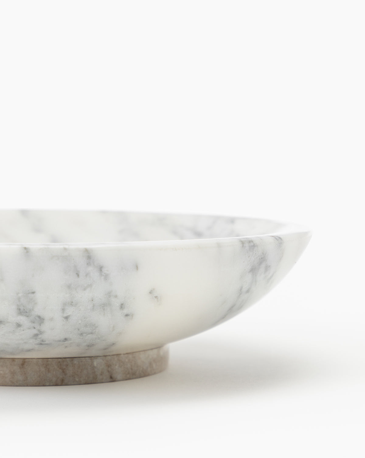 The Arabesco Marble Bowl, featuring a shallow, round shape and elegant gray and white veining, is partially visible against a plain white background.