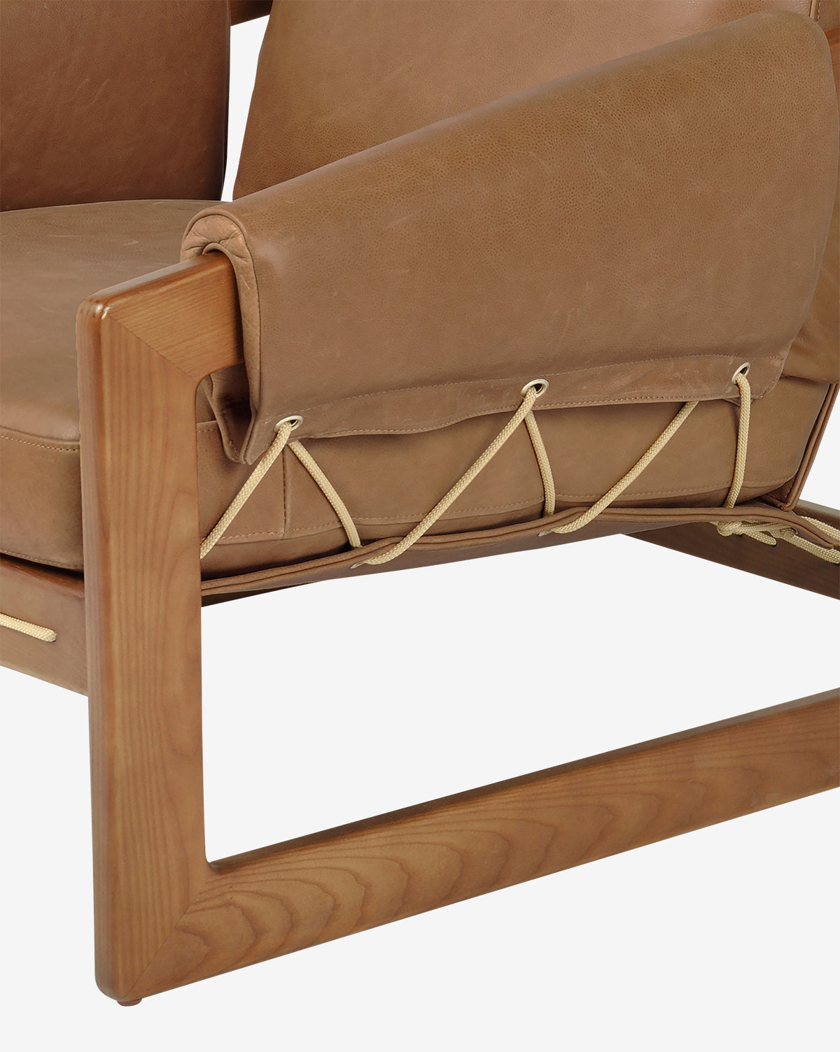 Close-up of the Barker Lounge Chair, featuring a wooden frame, top-grain leather cushions, and beige cord lacing on the armrest and seat, showcasing its craftsmanship and midcentury sling seating style, by McGee & Co.