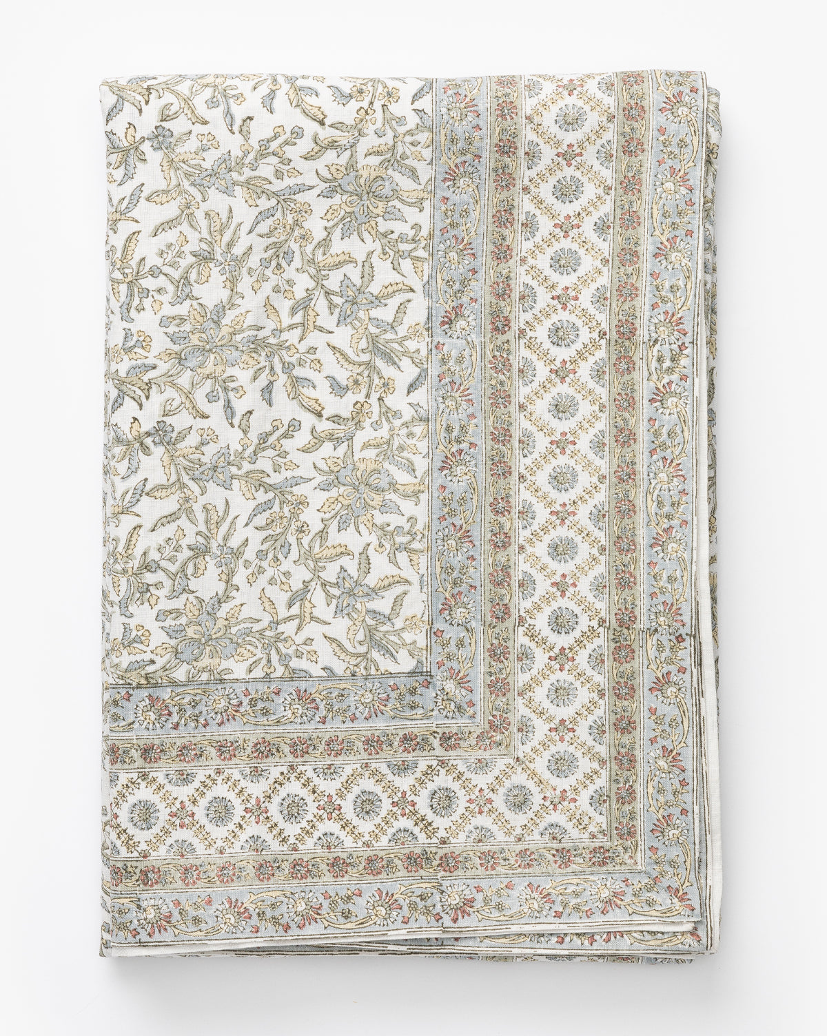 The Estelle Block Print Tablecloth is a folded linen-cotton piece featuring an intricate floral and geometric design in soft beige, blue, and pink on white, with a border of repeating diamond shapes and small flowers, by McGee & Co.