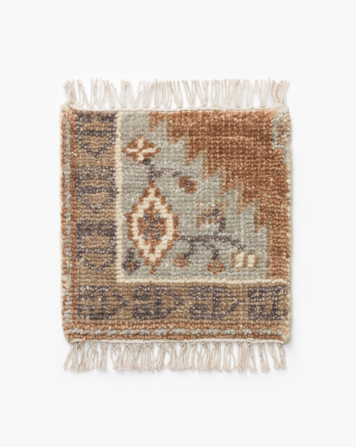 The Estrella Hand-Knotted Wool Rug Swatch is a small, square sample with fringed edges and a geometric floral pattern in earthy brown, beige, blue, and gray tones, by McGee & Co.