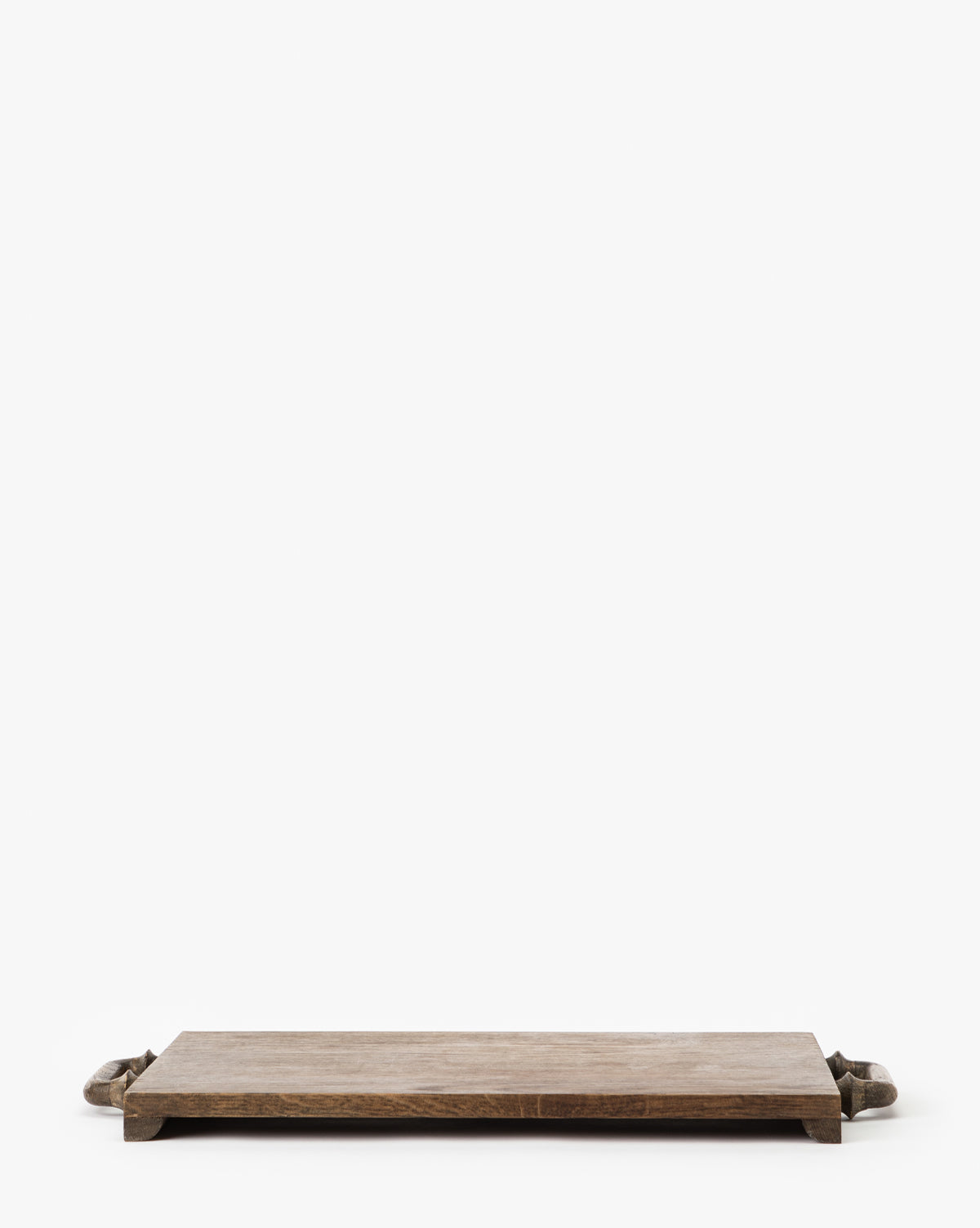 The Fordham Board is a rectangular solid oak wood serving tray with short legs and handles, ideal for serving charcuterie, displayed on a white background, by McGee & Co.