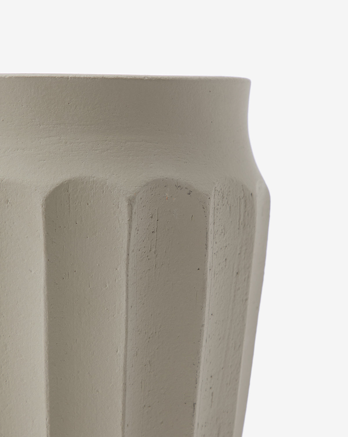 A close-up of the Frida Vase, a light beige, hand-glazed ceramic piece with vertical ridges and a curved upper edge, set against a plain white background.