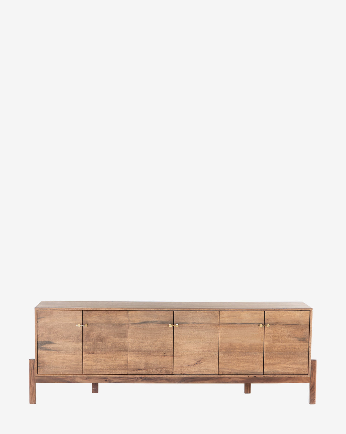The Gustav Console is a low, rectangular piece with four cabinet doors, small gold handles, and short legs. Its natural rustic wood finish and discreet media cord management make it ideal for mid-century style interiors, by McGee & Co.