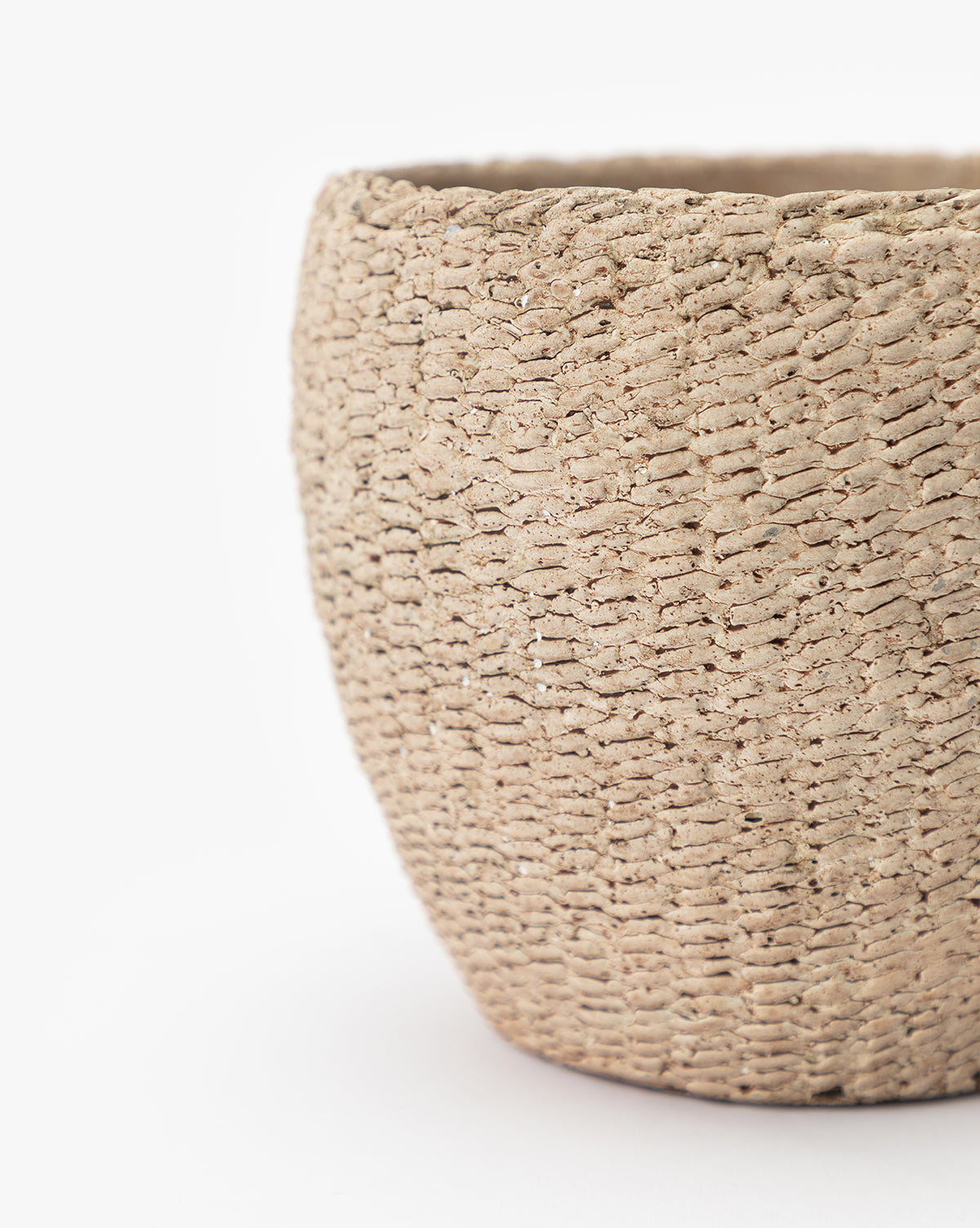 Close-up of the Halston Cement Planter, a textured beige basket-style planter with intricate weaving details and a natural, rough finish. Sturdy construction is showcased against a white background, with part of the left side out of frame.