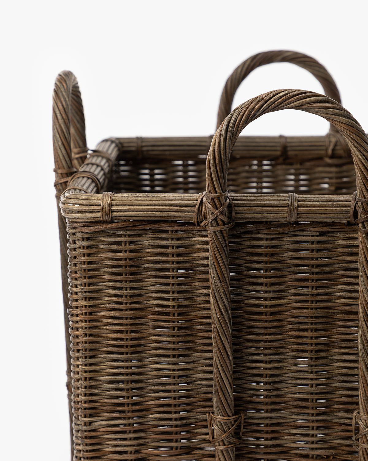 A close-up of the Jacinta Woven Basket, a rectangular wicker design with sturdy handles and organic texture, showcasing detailed craftsmanship in natural brown tones against a plain white background.