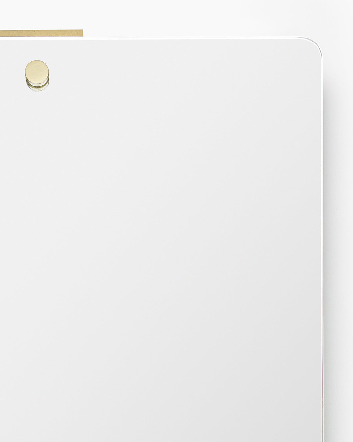 A minimal white magnetic dry erase board with rounded corners and a single gold magnet near the top left, designed to complement the Jacob Rectangular Mirror or a brass frame, placed against a plain white background, by McGee & Co.