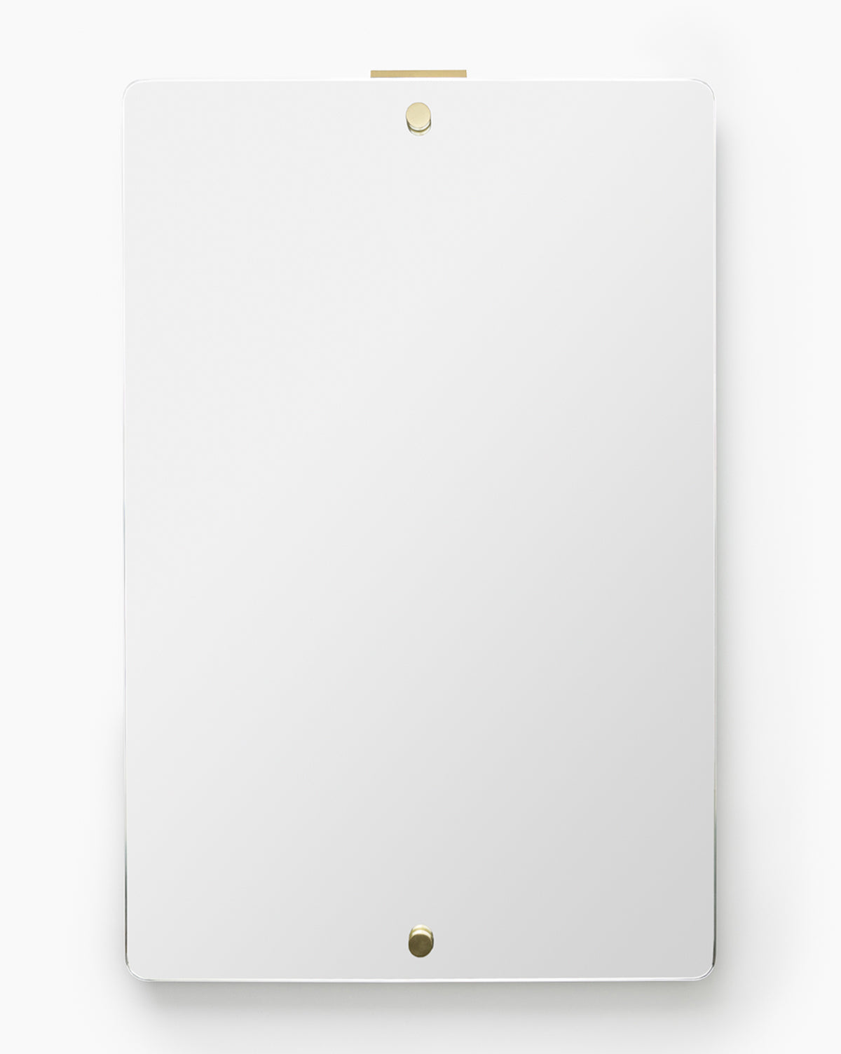 The Jacob Rectangular Mirror, featuring a frameless design with rounded corners, is mounted vertically on a white wall and secured by two small, round, gold-colored fasteners at the top and bottom, by McGee & Co.