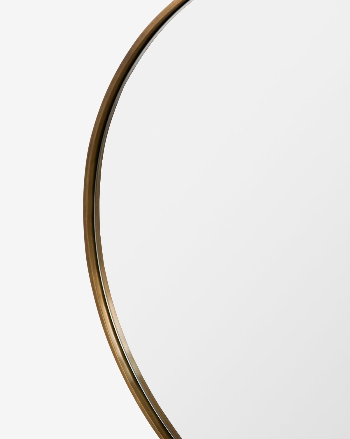 A close-up of the Laila Circle Mirror featuring a thin, metallic brass frame shown against a plain white background, by McGee & Co.