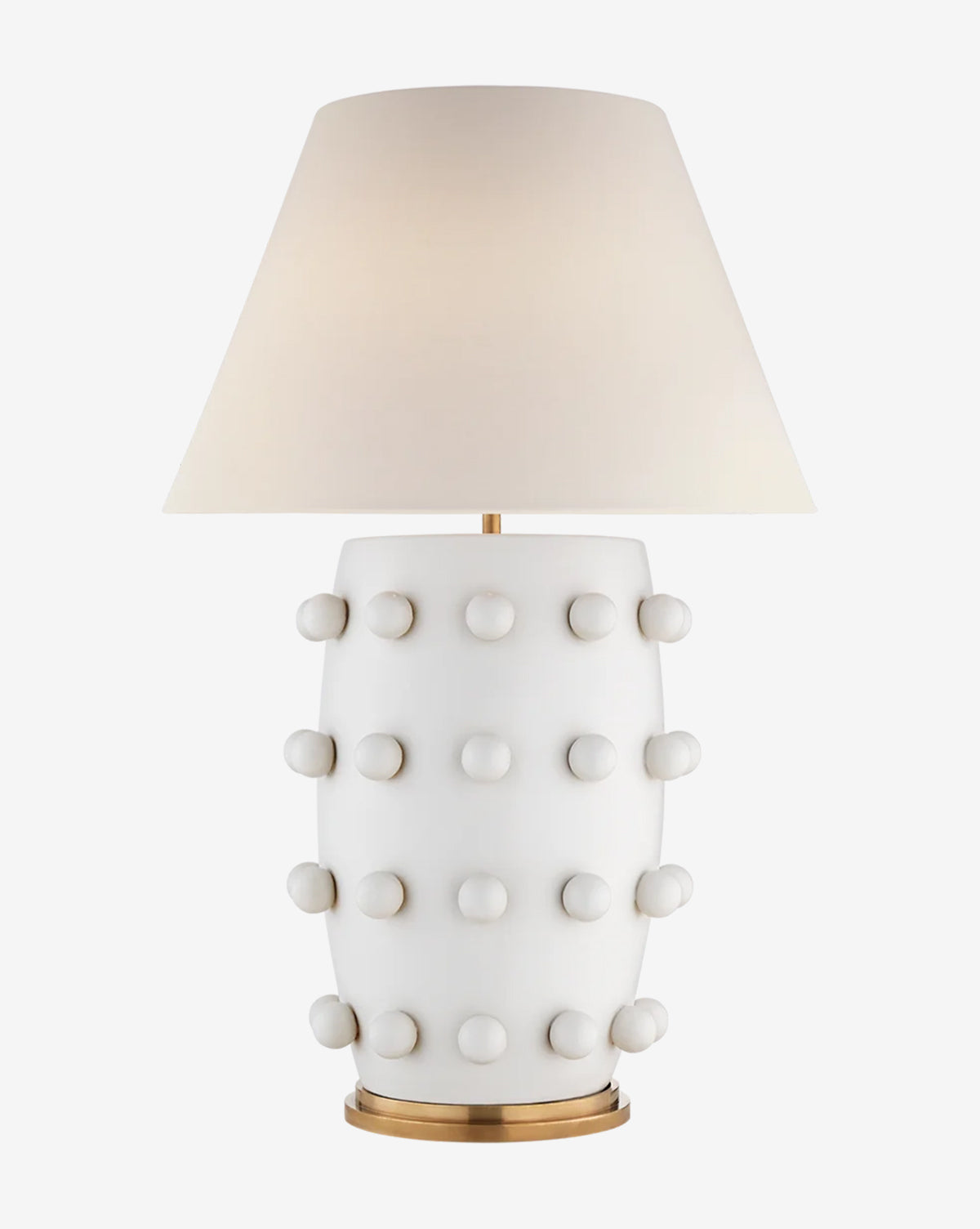 The Linden Table Lamp features a modern white ceramic base with raised knobs, a wide linen shade, and a gold-colored circular base for timeless elegance, by McGee & Co.