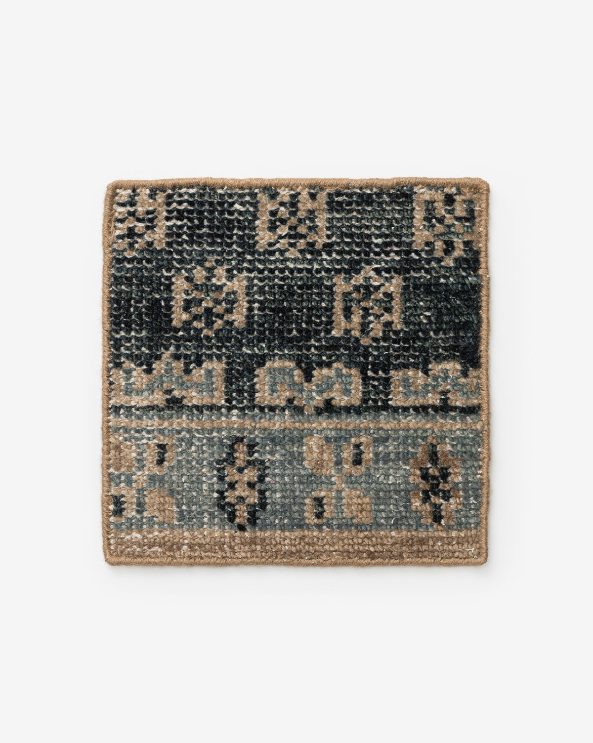 The Anya Indigo Hand-Knotted Rug Swatch by Obeetee features a square woven design with geometric patterns in black, gray, and tan tones with a tan border, inspired by transitional rugs, shown on a white background by McGee & Co.