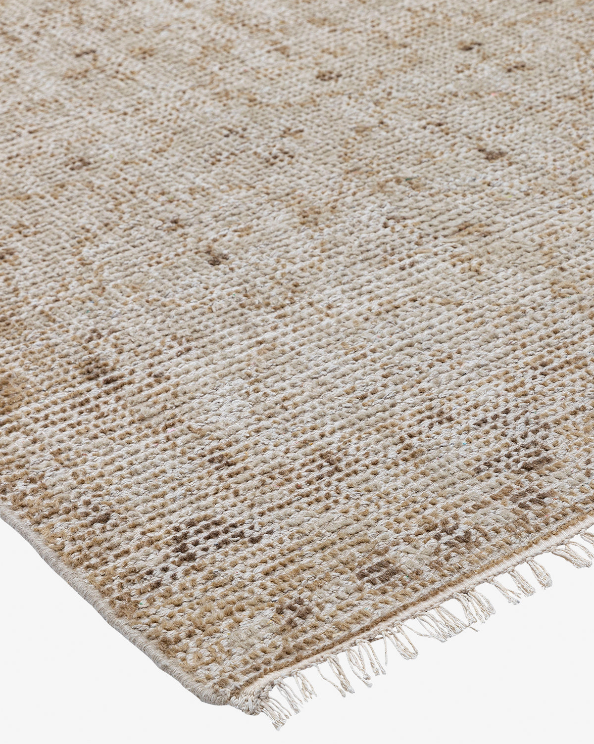 A close-up of the Mali Hand-Knotted Rug showcases its neutral tones, subtle geometric patterns, and small fringe tassels along one edge, featuring a textured, slightly rustic look, by McGee & Co.