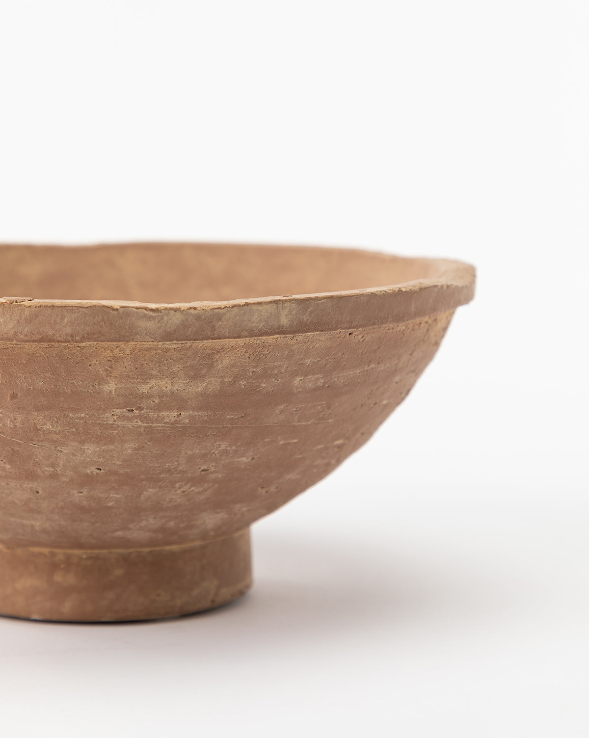 A close-up of the Theoden Terracotta Bowl—a rustic, hand-thrown piece with a shallow form and cylindrical base—set against a plain white background. Only half of the bowl is visible in the image.