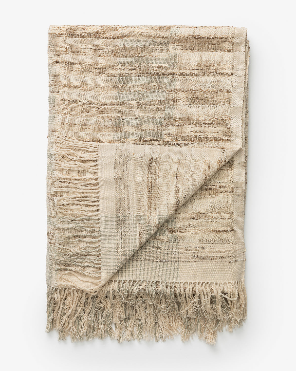 The Theodora Block Stripe Throw, made from beige cotton and raw silk with subtle brown stripes and textured fringe, is shown partially folded on a white background.