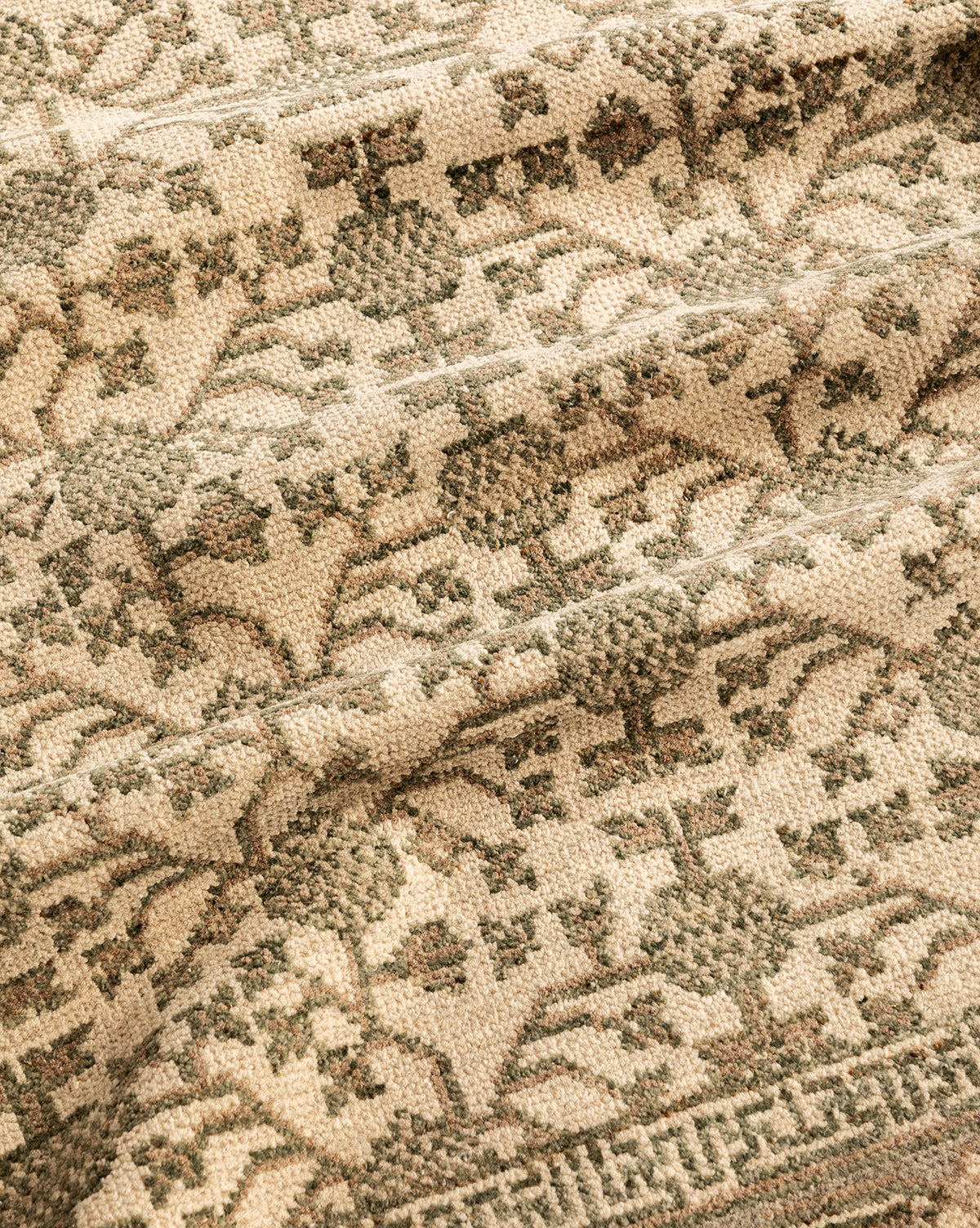 A close-up of the Orsino Hand-Knotted Rug shows its beige and green vintage-inspired floral and geometric patterns, with detailed weaving and texture for an authentic antique look, by McGee & Co.
