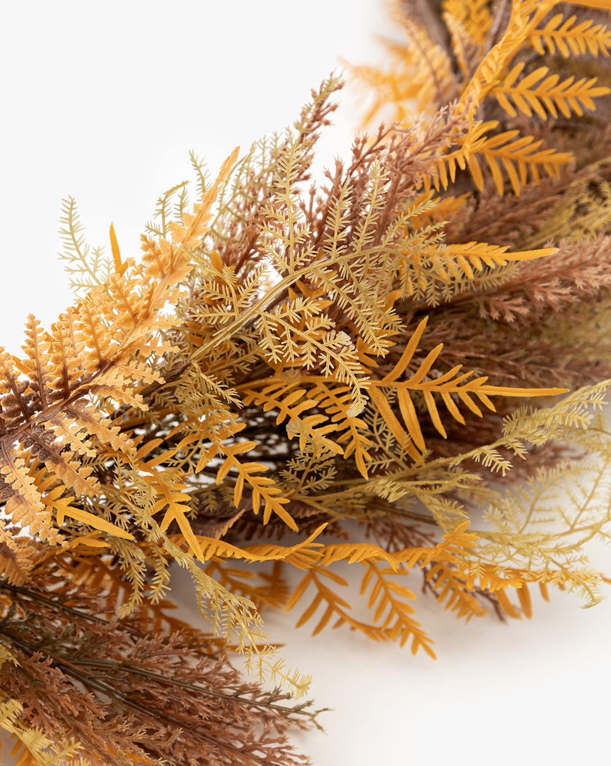 A close-up of the 6 Faux Golden Fern Garland, featuring yellow, orange, and brown hues against a white background—ideal for autumn décor, by McGee & Co.