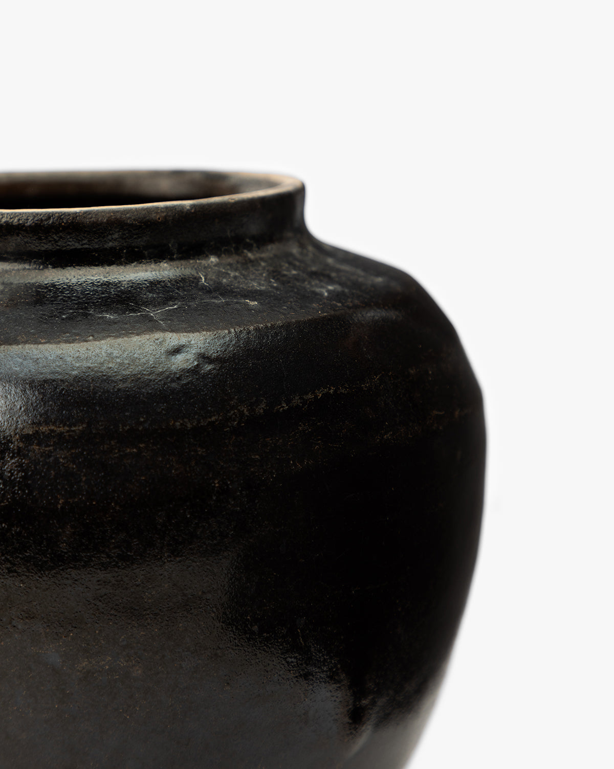 Close-up of the Agnes Vase, a round, dark ceramic piece with a wide opening and smooth, subtly reflective surface, shown against a plain white background. Only the upper side and portion of the vase are visible, by McGee & Co.