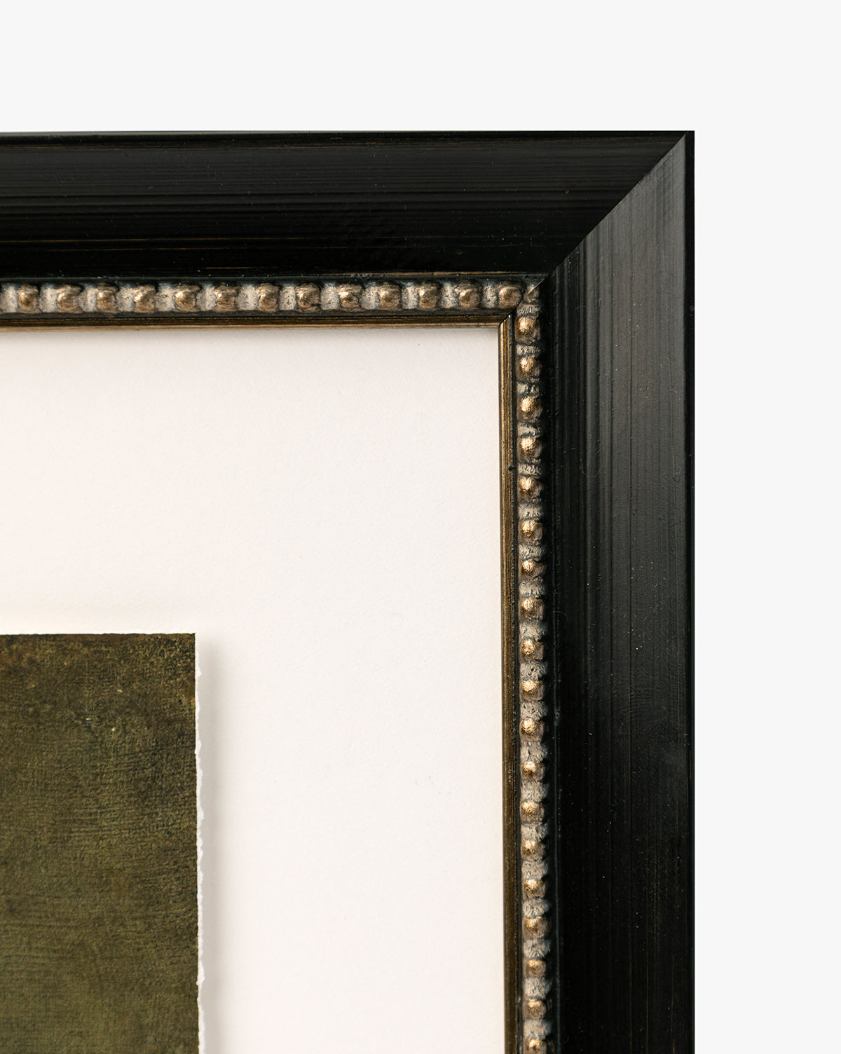 Close-up of the top right corner of a black wooden picture frame with beaded detailing and a white mat, showcasing the edge of Antique Flower Vase green-toned vintage-inspired wall art, by McGee & Co.
