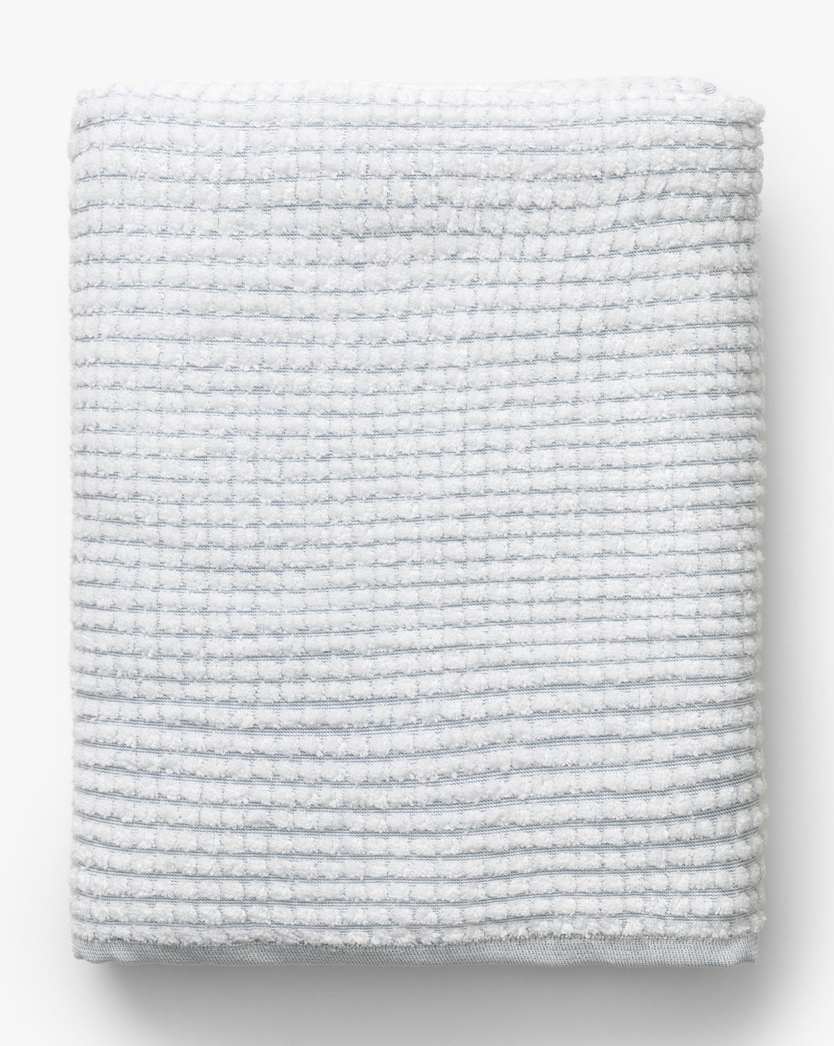 A neatly folded gray towel with a textured, grid-like pattern from our Atrani Gray Organic Bath Collection, displayed on a plain white background by McGee & Co.