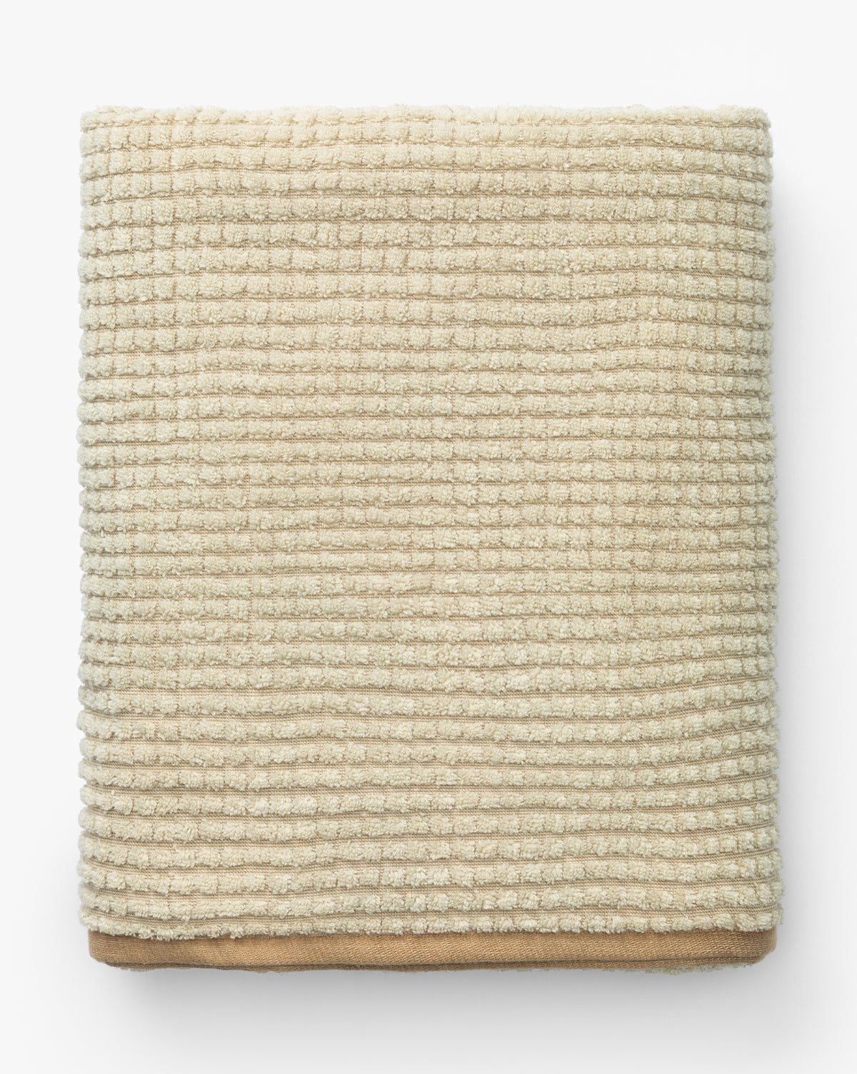 A neatly folded, beige, waffle weave towel from the Atrani Organic Bath Collection is placed on a white background by McGee & Co.