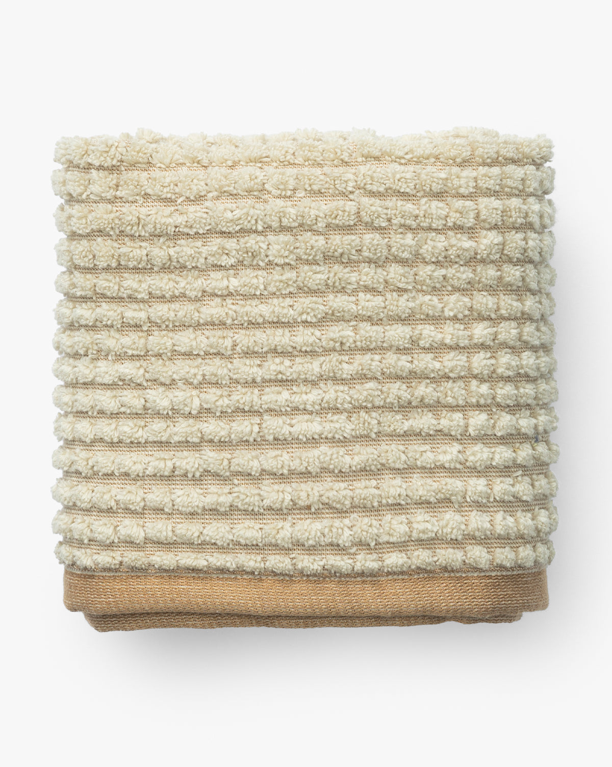 A neatly folded, ribbed beige towel from the Atrani Organic Bath Collection is stacked on a plain brown organic cotton towel, both set against a white background, by McGee & Co.