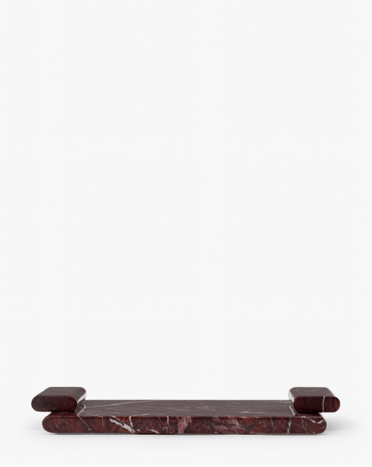 The Auburn Marble Tray is a low, rectangular tray crafted from auburn marble with white veining, rounded edges, and raised cylindrical ends, offering an elegant decorative accent against a plain white background, by McGee & Co.