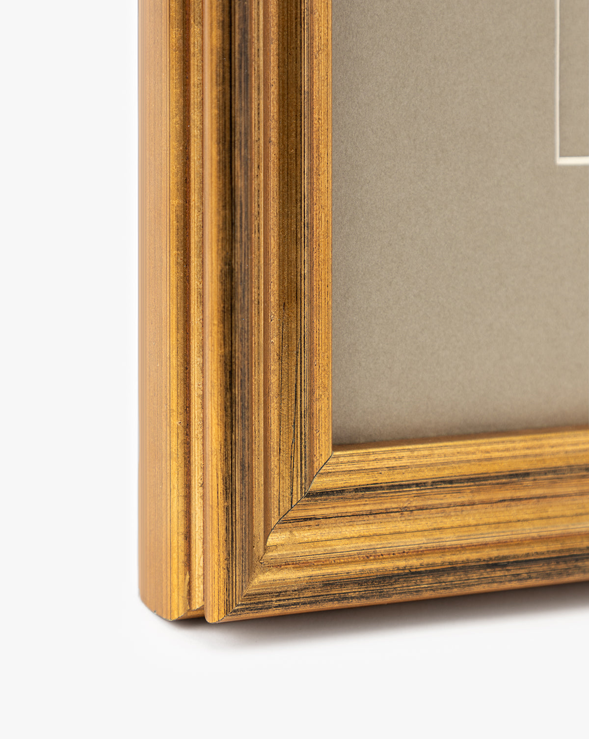 Close-up of the corner of an antique gold frame with a grooved design and beige mat, ideal for displaying Blossoming Branch wall art or petite florals, by McGee & Co.