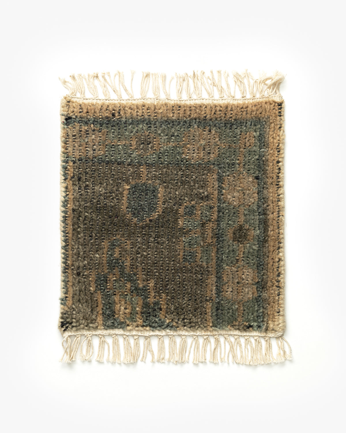 The Chevalier Hand-Knotted Rug Swatch is a small, rectangular wool piece with fringed edges, showcasing a vintage-inspired beige, brown, and green geometric pattern on a plain white background by McGee & Co.
