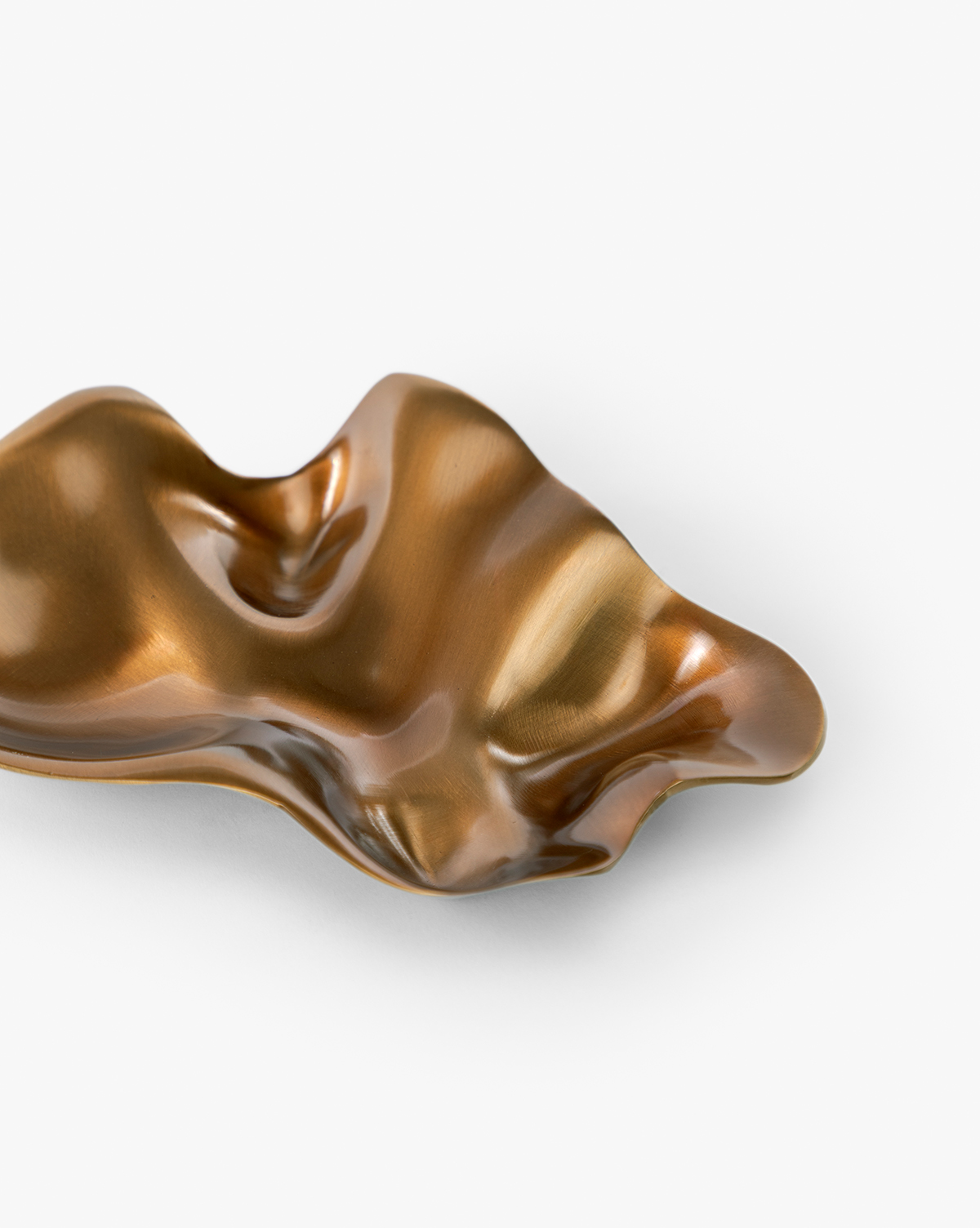 A shiny, abstract bronze dish with a metallic finish and wavy surface is displayed on a white background, showcasing modern artistry in the unique Chiffonner Metal Object, by McGee & Co.