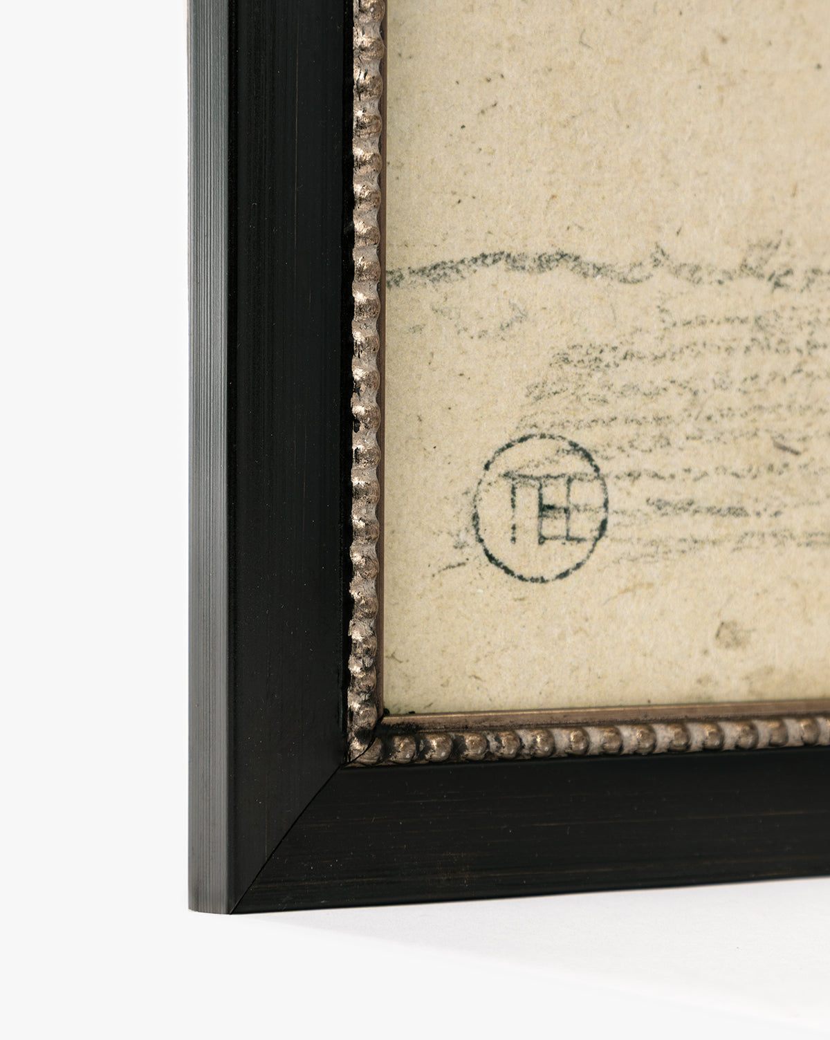 Close-up of a framed Clouded Island giclée on paper, showing its black frame with textured inner border and part of a faded circular stamp on the aged artwork, by McGee & Co.